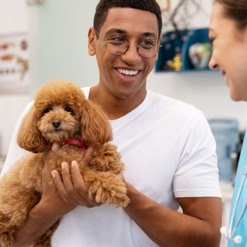 Man holding a small dog at the vet